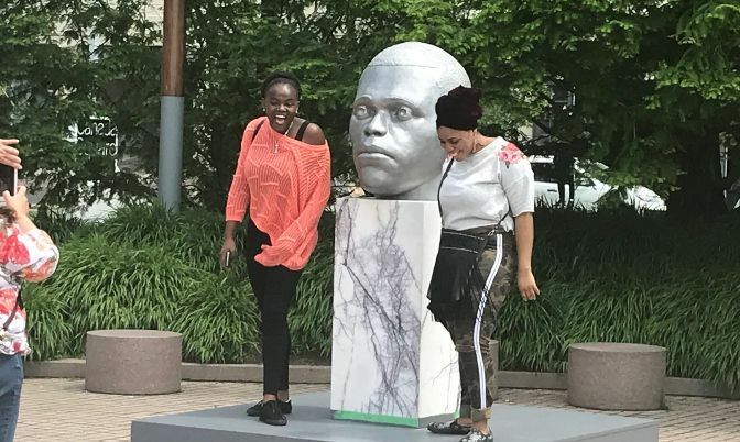 Women posing with Thomas J Price's Ordinary Men Exhibit at Toronto’s Powerplant Contemporary Art Gallery