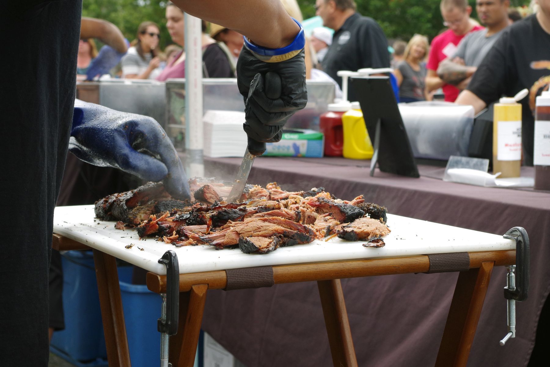 Person wearing gloves chops smoking meat