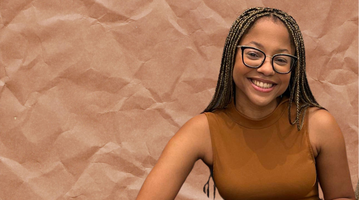 A smiling woman with long, tightly braided hair and black rectangular glasses poses on the right side of the image. She wears a sleeveless brown top and faces the camera. The left side contains open space, while the background is a crumpled, textured sheet in warm tan and brown tones.